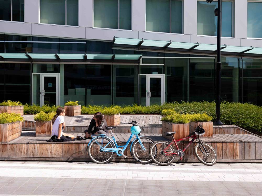 Two women relax while seated on the custom wood benches next to their bikes.