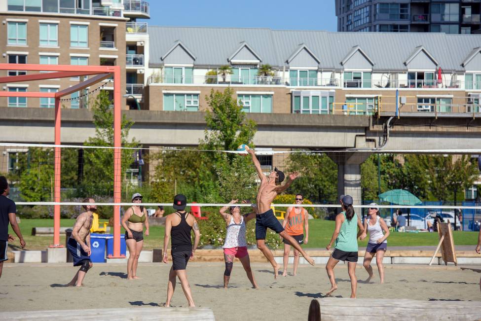 A group of young adults engage in a game of volleyball on the sandy court.