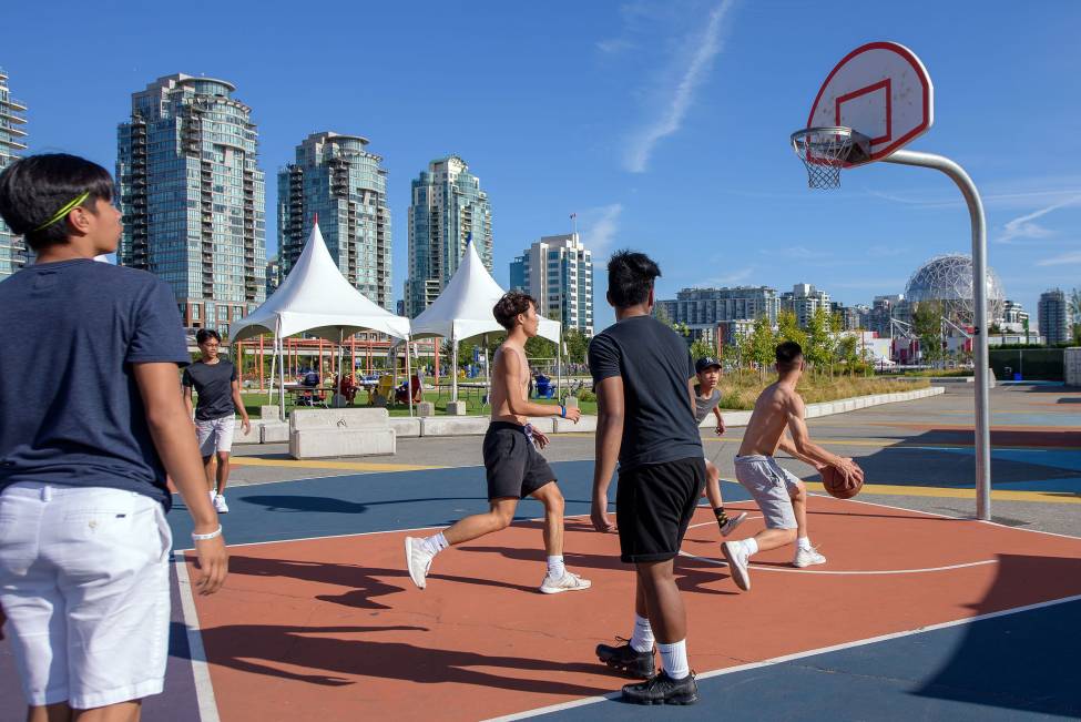 Boys scrimmage on the basketball court on a sunny day.