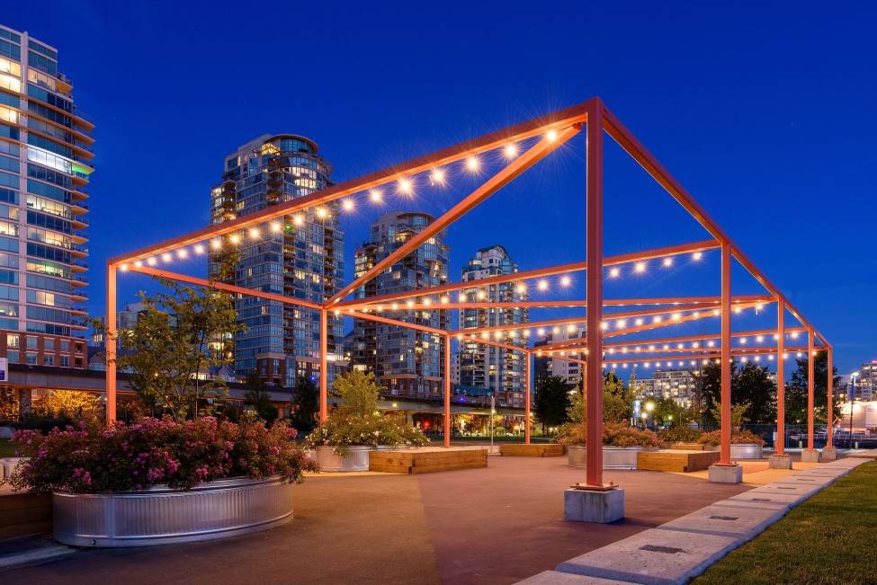 A structure around the planting beds is lit up at night time.