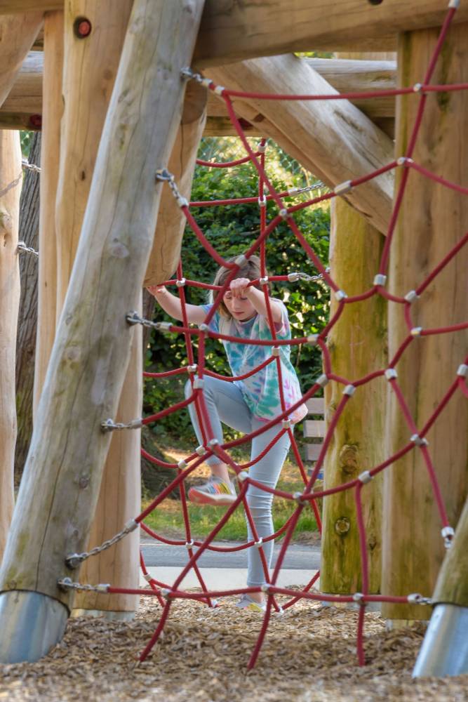 A child climbs the rope net on the playground.
