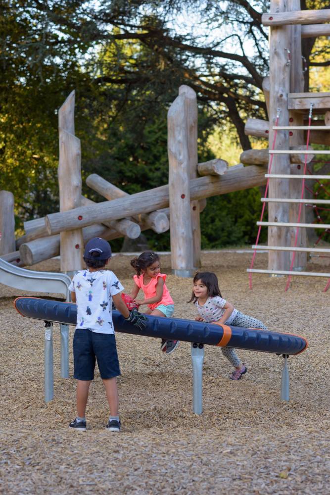 Three kids smile while playing on the playground.