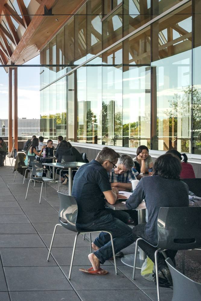 Many students studying at the chairs & tables on the rooftop.