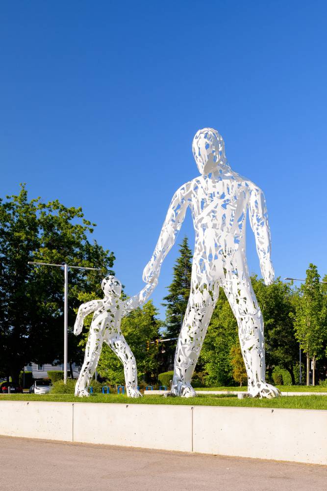 Public art installation outside the Aquatic Centre, showing a large sculpture of an adult and child walking towards the entrance.