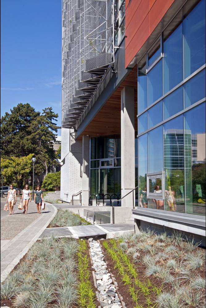 Three women walk past one of the building's entrances.