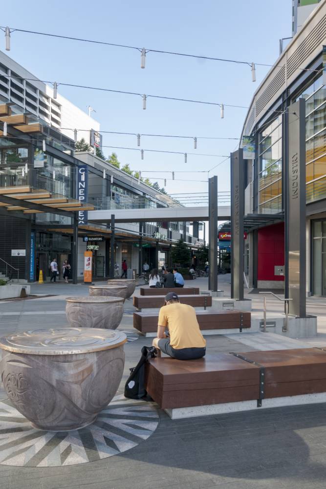 Man rests on one of many benches at Marine Gateway plaza.
