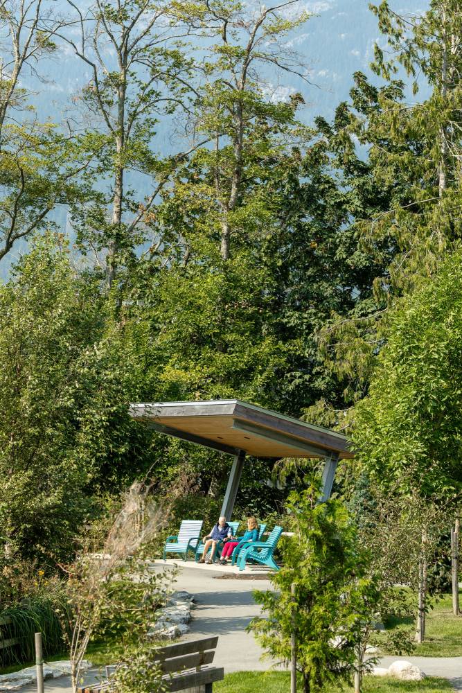 Two people sit in one of the shelters at the park.