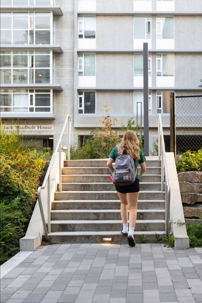 A women with a backpack walks up a small staircase.