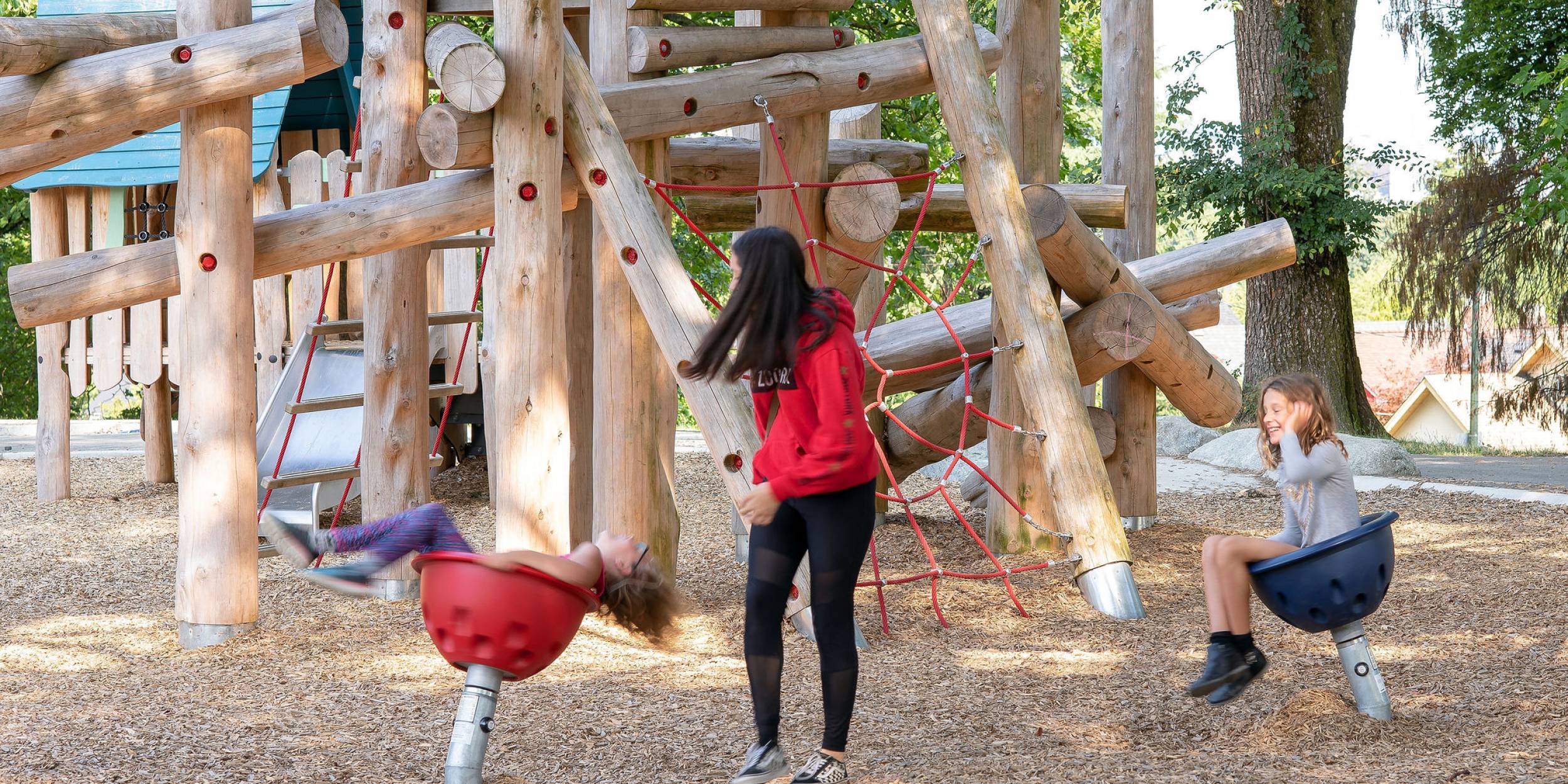 A parent and two children play on Clark Park playground.