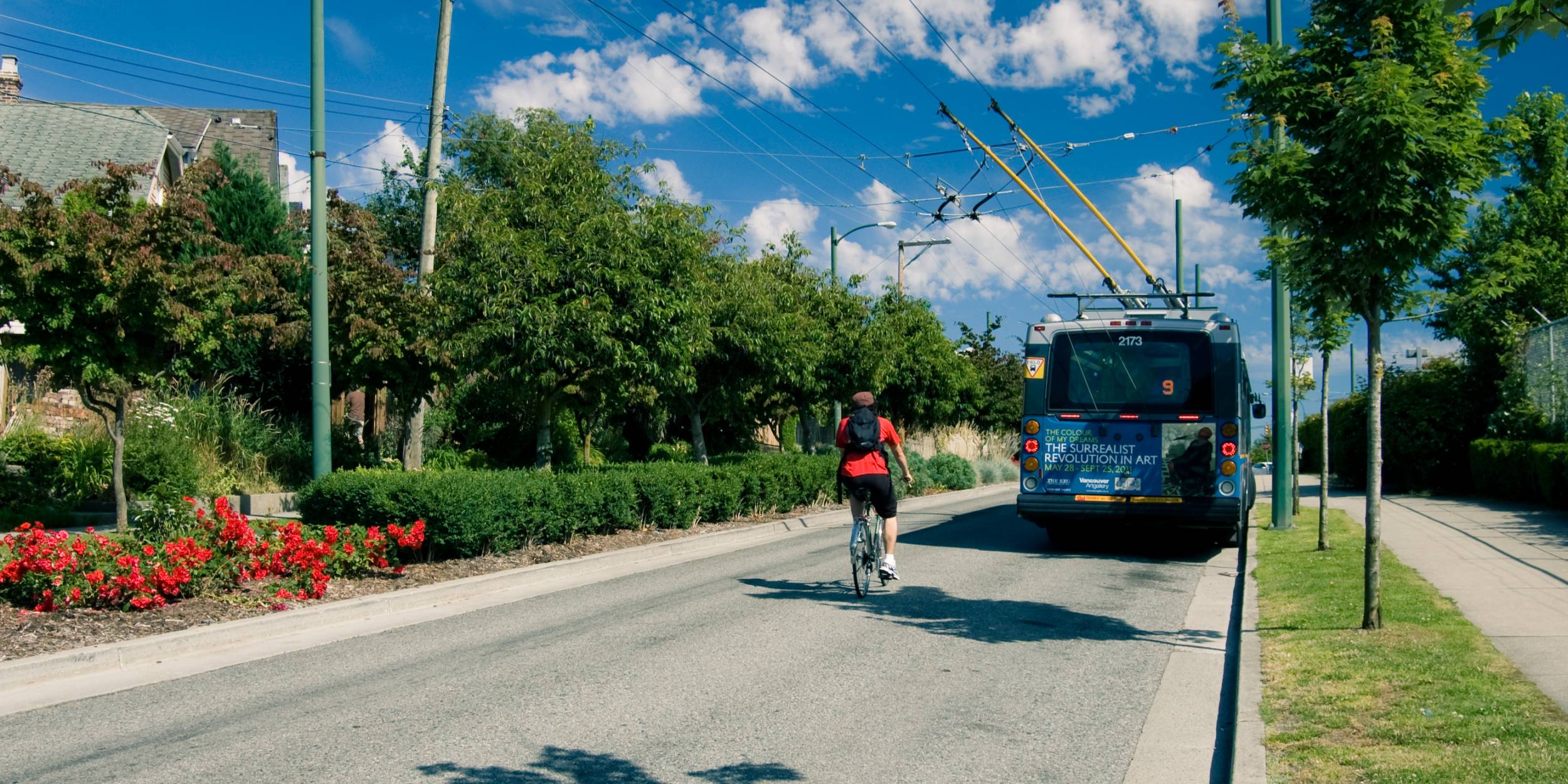 A man bikes along the Central Valley Greenway, as the #9 bus drives nearby.