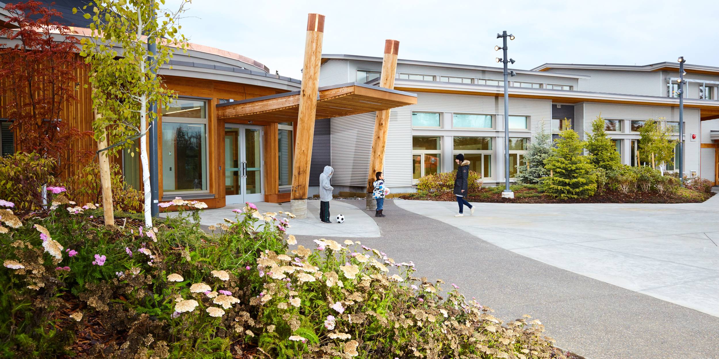 Three children play with a soccer ball outside of the community centre.