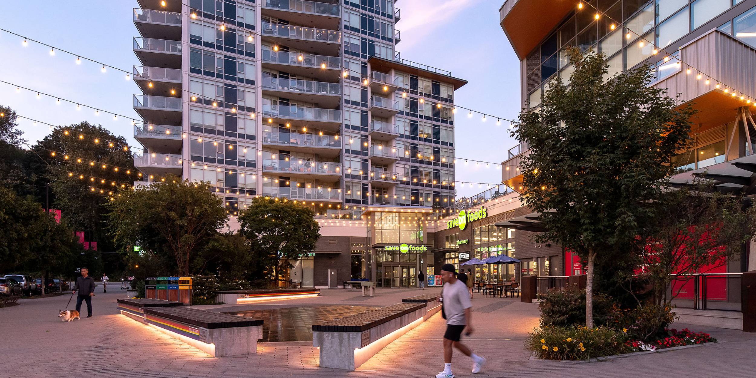 View of River District's town centre plaza at dusk.