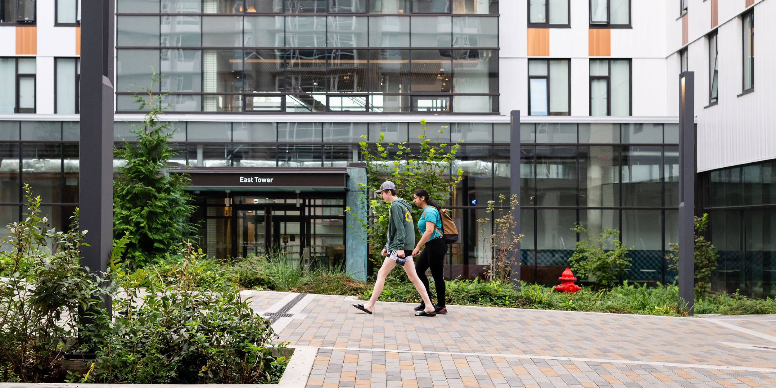 Two students walk past the East Tower residence building.