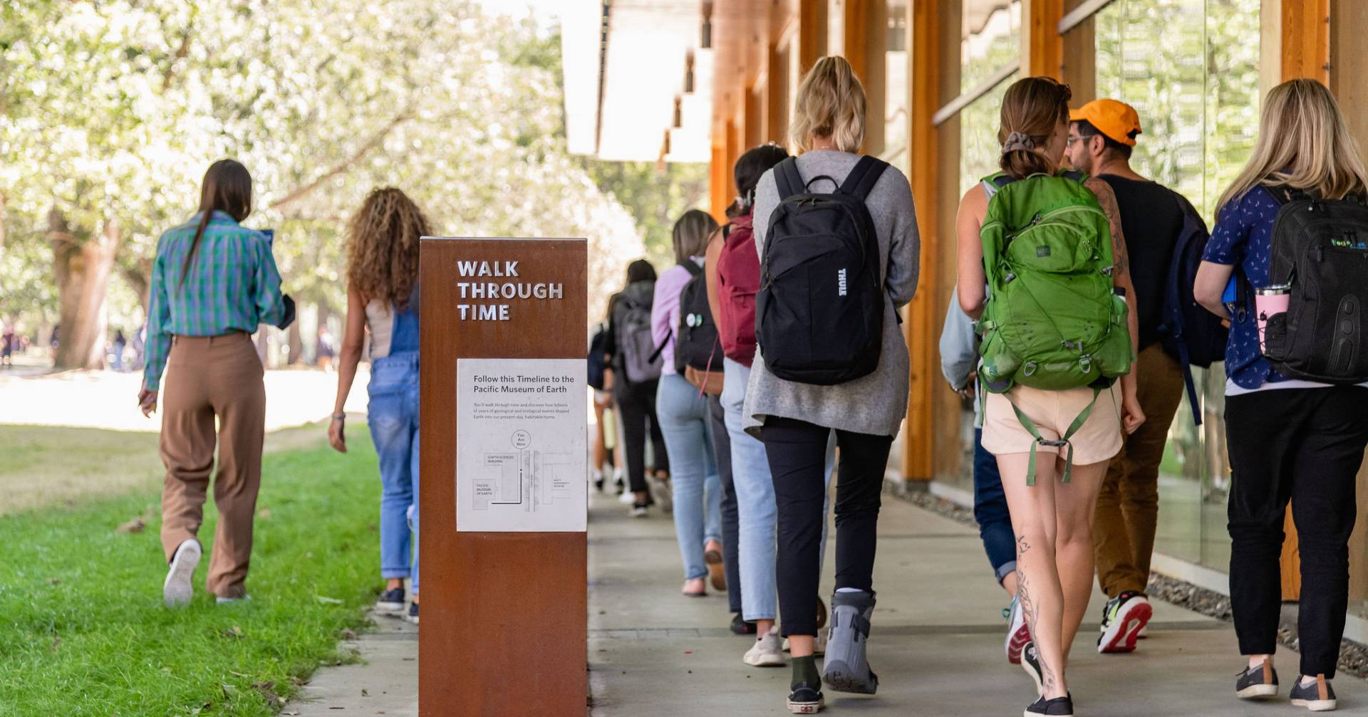 Students walk past interpretive signage.